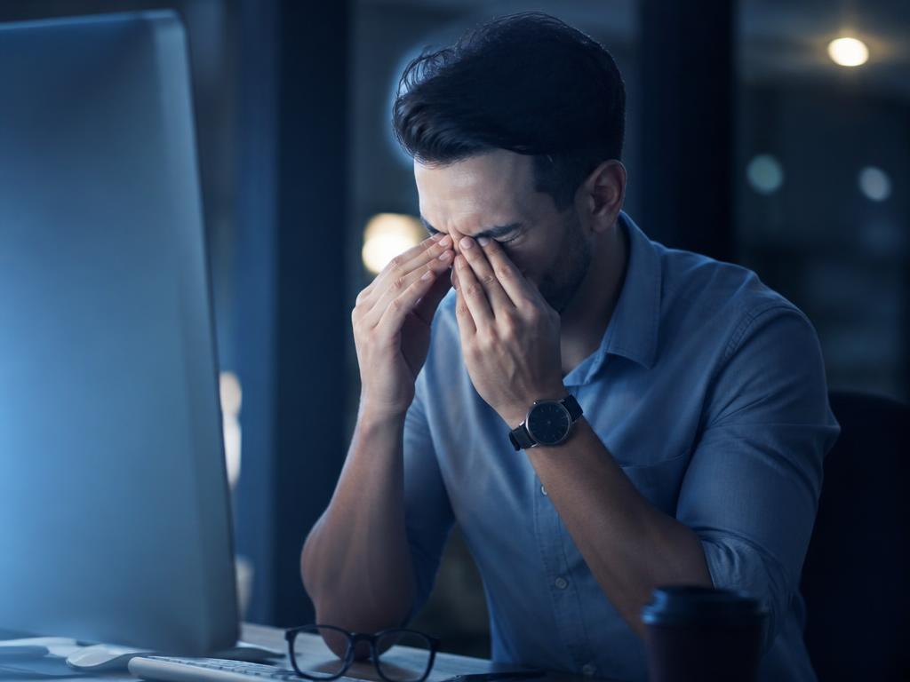 Person mit müden Augen vor einem Bildschirm bei Nacht